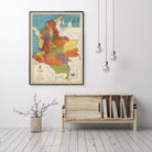 a framed map of Colombia hanging on a wall, with a wooden cabinet below it and a vase of flowers on the floor.