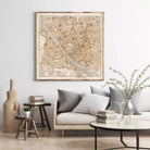 a living room with a large framed map of Florence, Italy, hanging on the wall above a couch with pillows. The room also includes a coffee table with books and a vase with greenery.
