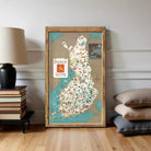 A framed map of Finland is displayed on a wall, with a stack of books and a lamp to the left.