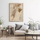 a living room with a large framed map hanging on the wall above a gray sofa with striped pillows. The room has a wooden coffee table, a side table with a plant, and a bookshelf with several books.