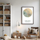 a cozy living room with a bookshelf filled with books, a lamp, a chair, and a teddy bear. A framed map of Oakland hangs on the wall, and a small wooden chest is placed on the floor.