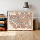 A framed map of Pittsburgh, Pennsylvania, with a lamp and books in the background.