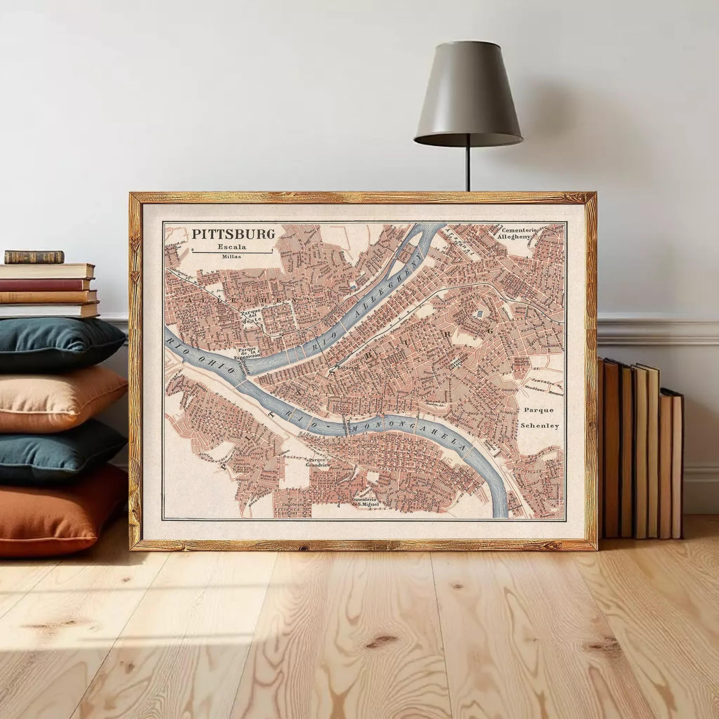 A framed map of Pittsburgh, Pennsylvania, with a lamp and books in the background.
