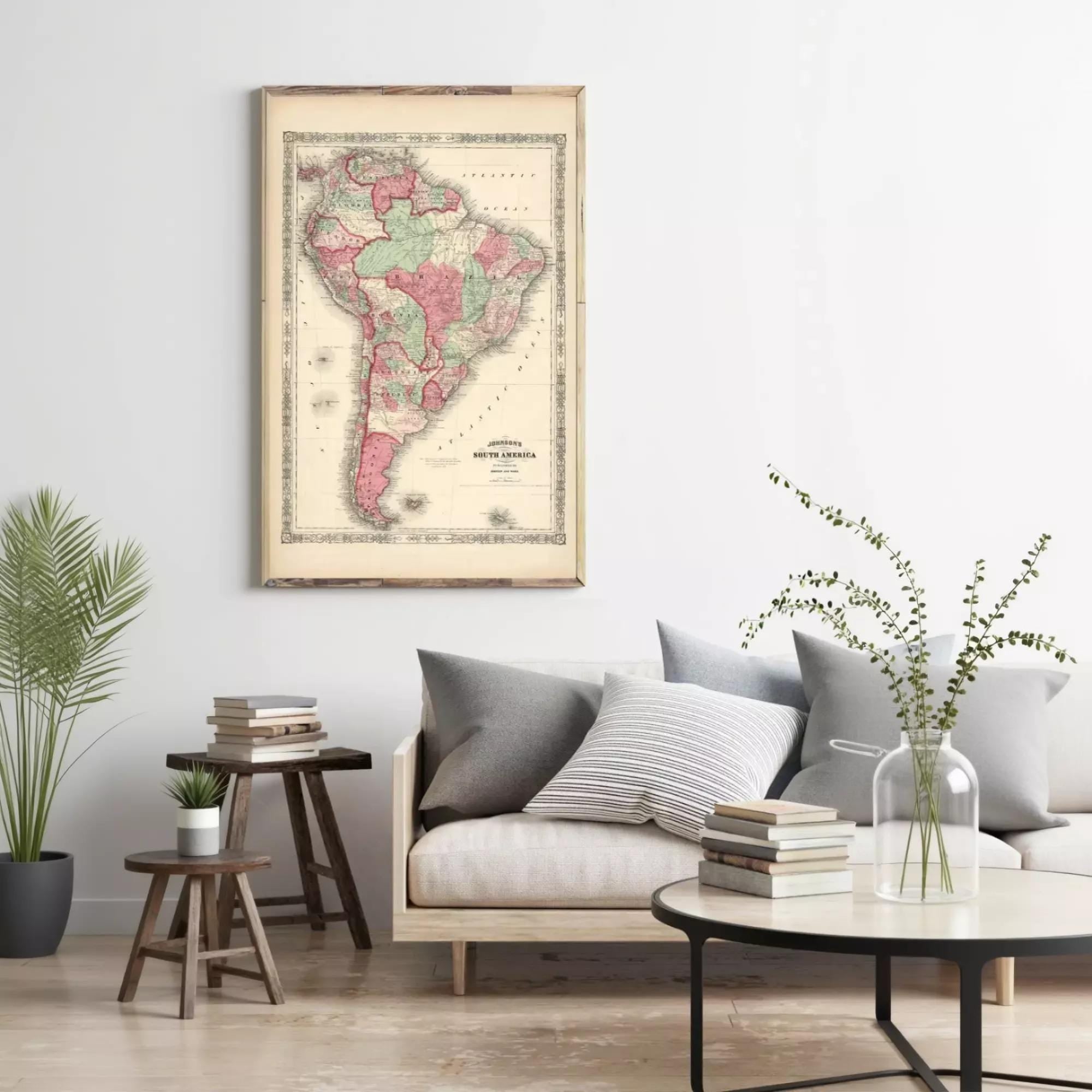 a living room with a large framed map of South America hanging on the wall above a couch with pillows. There are also some books and a vase with flowers on the couch, creating a cozy and inviting atmosphere.
