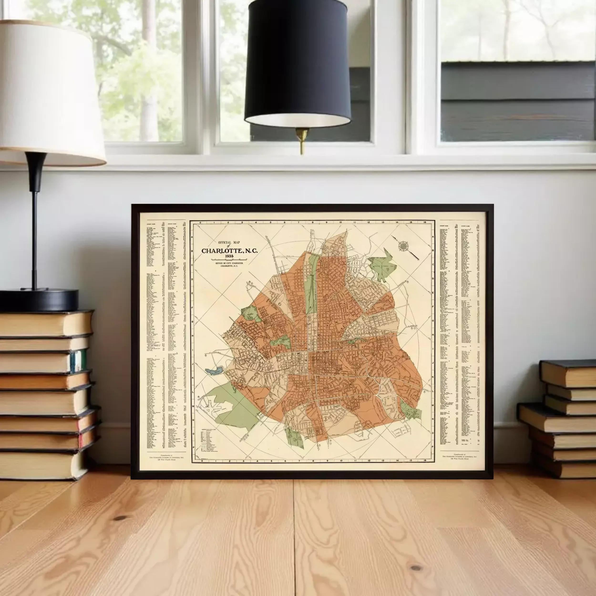 A framed map of Charlotte, North Carolina, displayed on a wooden floor in front of a window.
