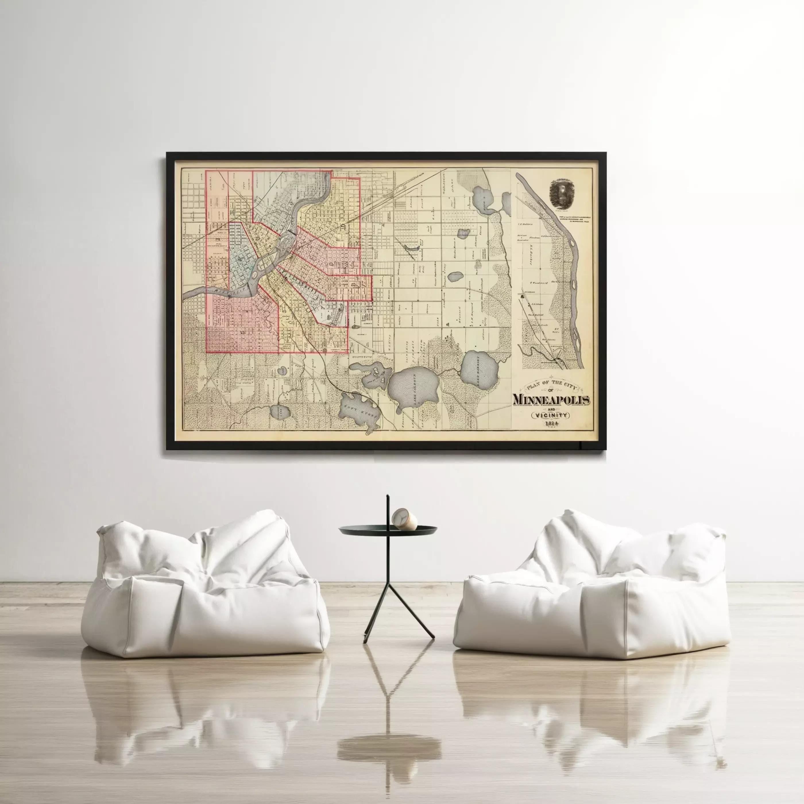 a large framed map of Minneapolis, Minnesota, with a black frame and a white background. The map is hung on a wall above a small table with two white bean bag chairs placed in front of it.