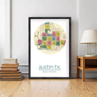 The image is a framed print of a map of Austin, Texas, with a central circular design featuring a color-coded grid of squares.