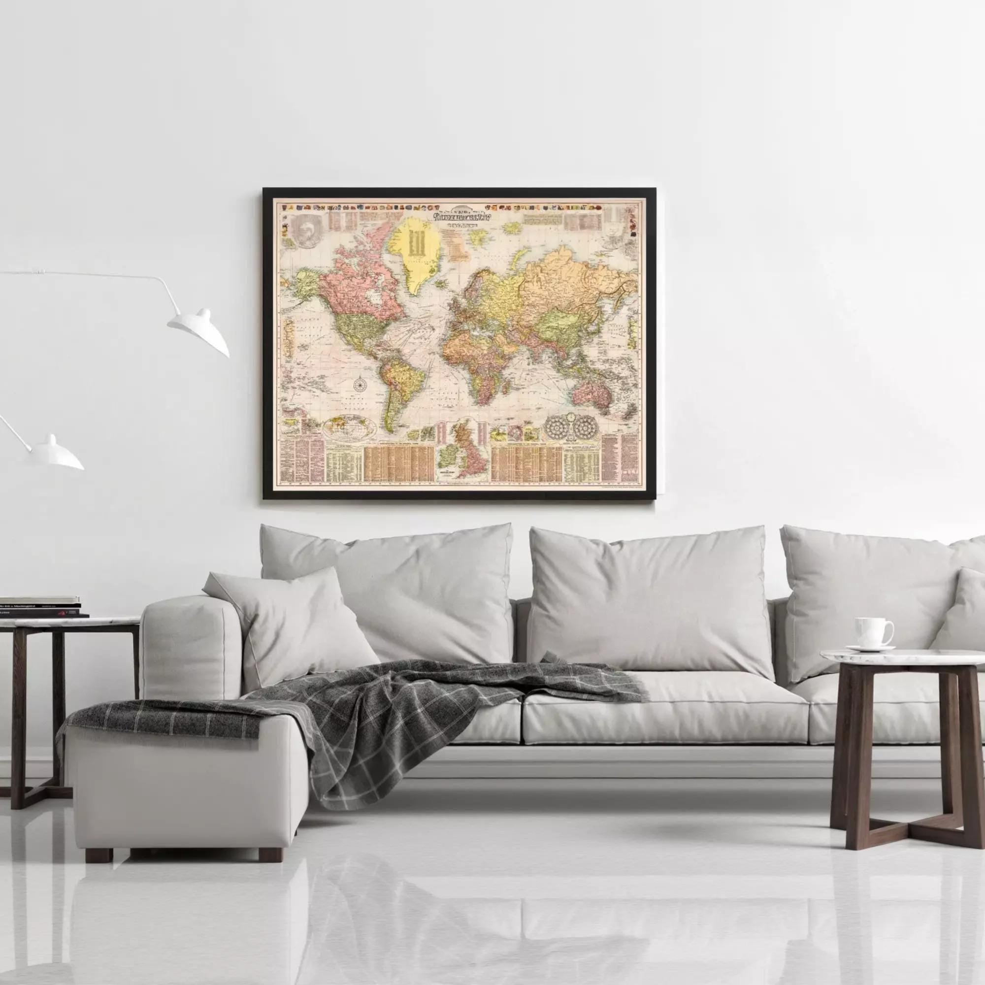 a large world map hanging on a white wall above a gray couch with a plaid throw blanket.