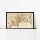 The image is a framed vintage map of a city, likely Paris, with a detailed and colorful depiction of the city's streets, landmarks, and surrounding areas.