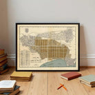 a framed map of Carmel by the Sea, with a stack of books and a few pencils on the floor in front of it.