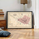 The image is a framed vintage map of a city, depicting a detailed layout of streets, buildings, and other urban features.