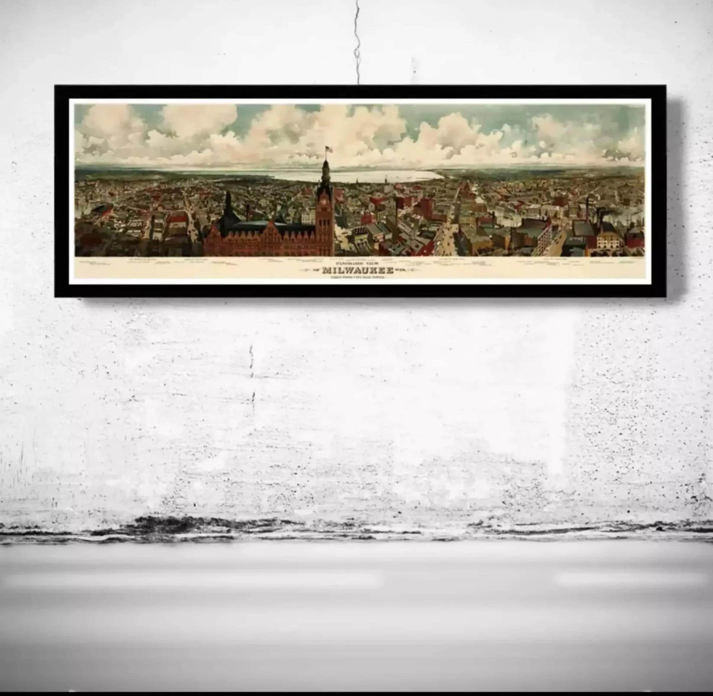 A framed painting depicting a cityscape with a tall building and a flag, hanging on a wall.