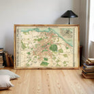 a large framed map of Edinburgh, Scotland, with a wooden floor and a stack of books in the background.