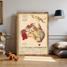 a framed geological map of Australia, with a color-coded legend and a small stuffed animal on the floor in front of it.