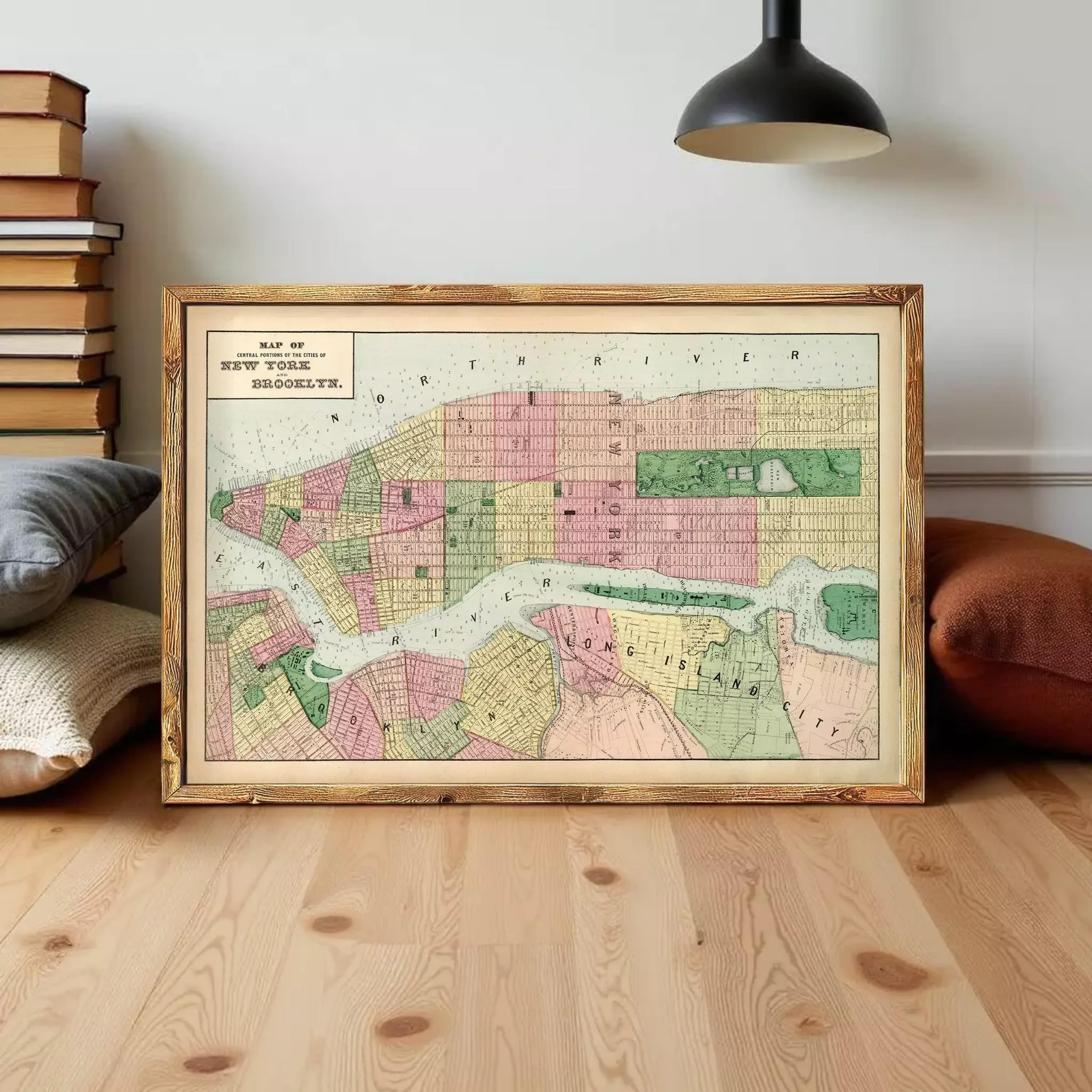 A framed map of New York City, depicting the city's streets and neighborhoods, is displayed on a wooden floor in front of a bookshelf.