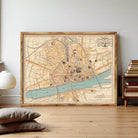 The image is a framed vintage map of a city, likely Paris, with various streets, landmarks, and a river depicted.