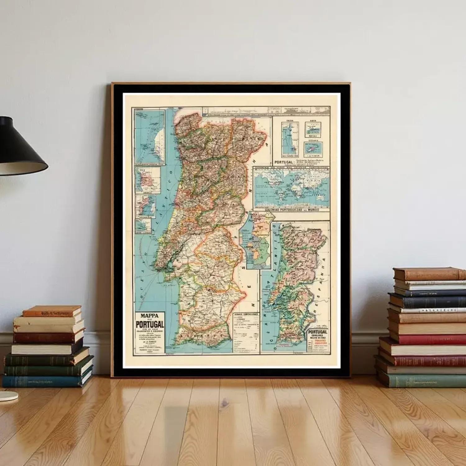 a framed vintage map of Portugal, with a stack of books and a lamp visible in the background.