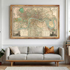 a large framed map of London hanging on a wall above a gray sofa with a brown throw pillow.