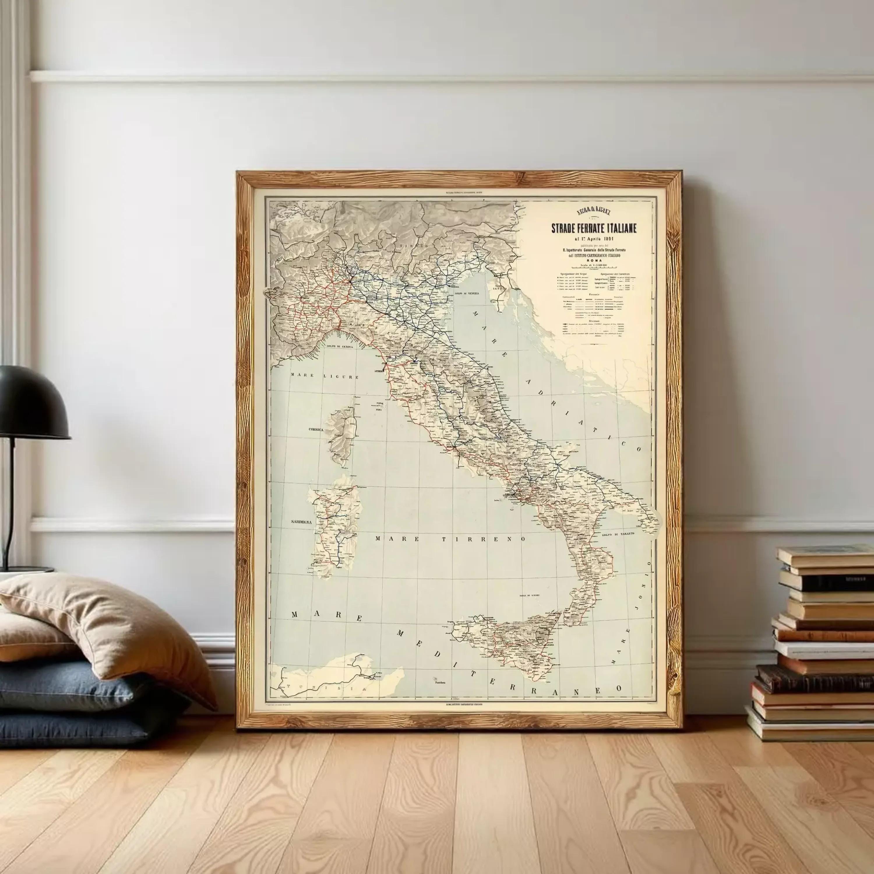 A framed vintage map of Italy is displayed on a wall, surrounded by a stack of books and a lamp.
