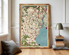 The image is a framed vintage map of a city, featuring a detailed and colorful depiction of the urban landscape.