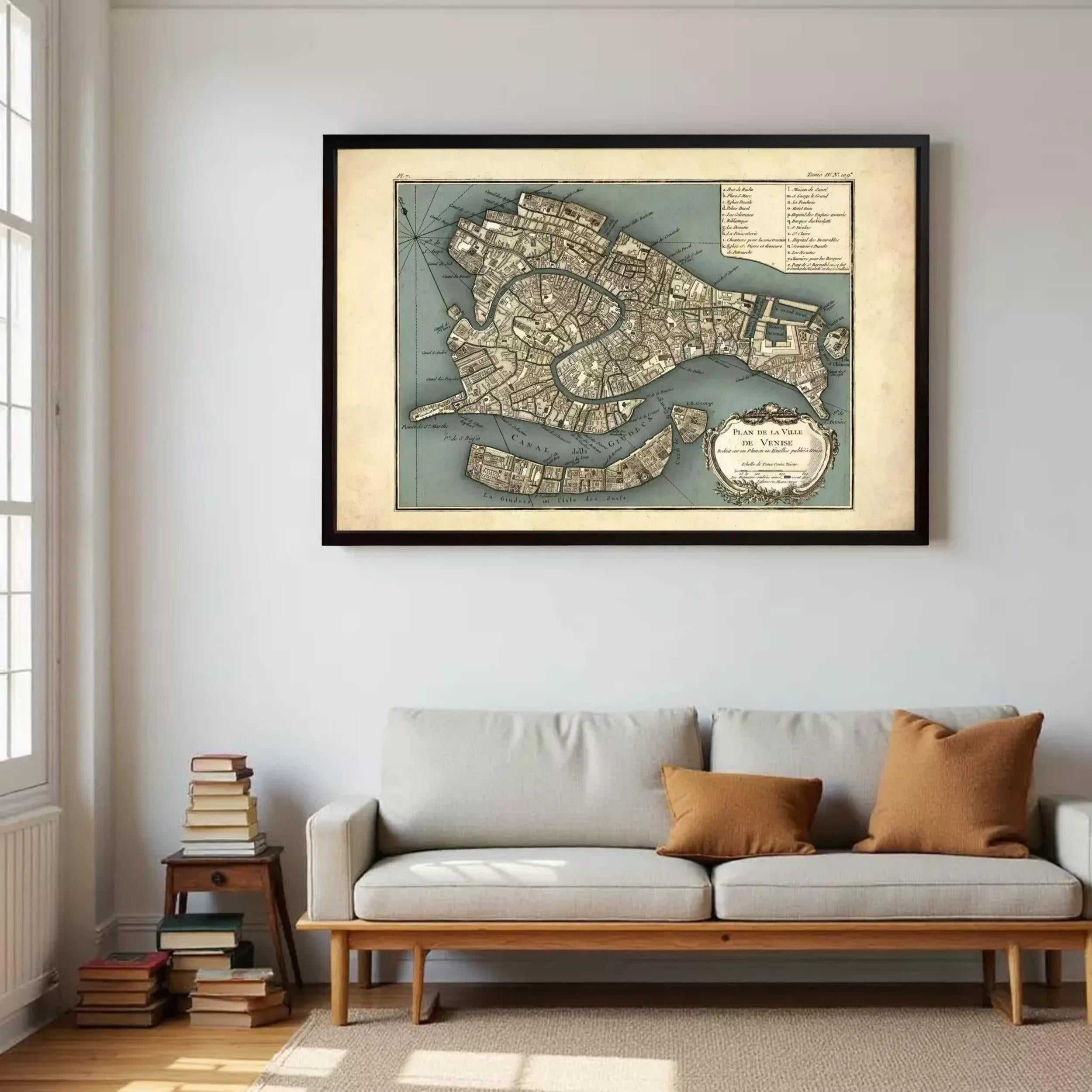 a large framed map of Venice hanging on a wall above a gray sofa with two pillows.