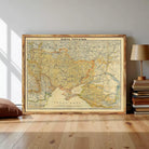 a large framed map of the world, with a wooden floor and a stack of books visible in the background.