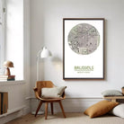 a living room with a wooden chair, a lamp, and a framed map of Brussels hanging on the wall.