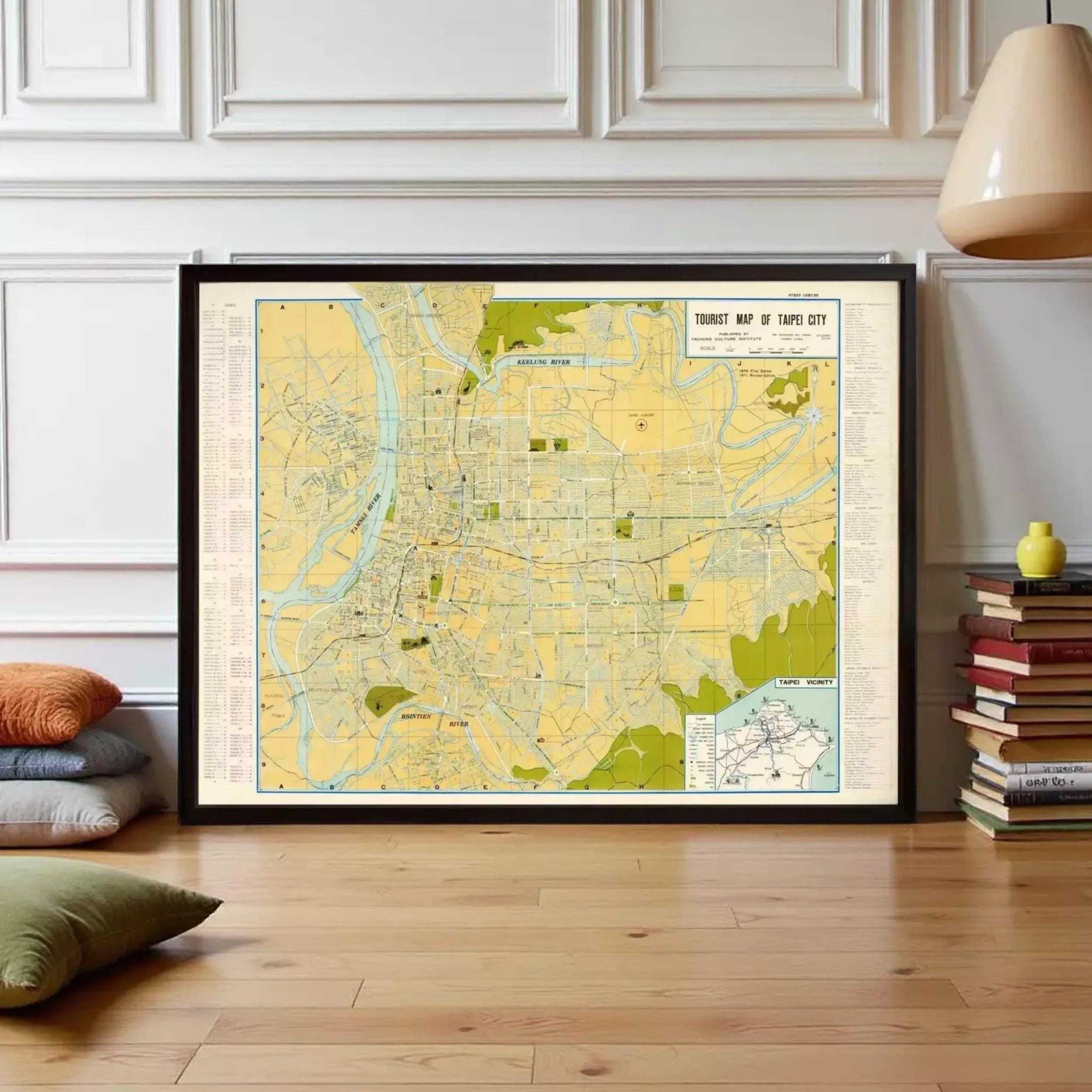 a large framed map of Taipei City, Taiwan, with a wooden floor and a stack of books to the right.