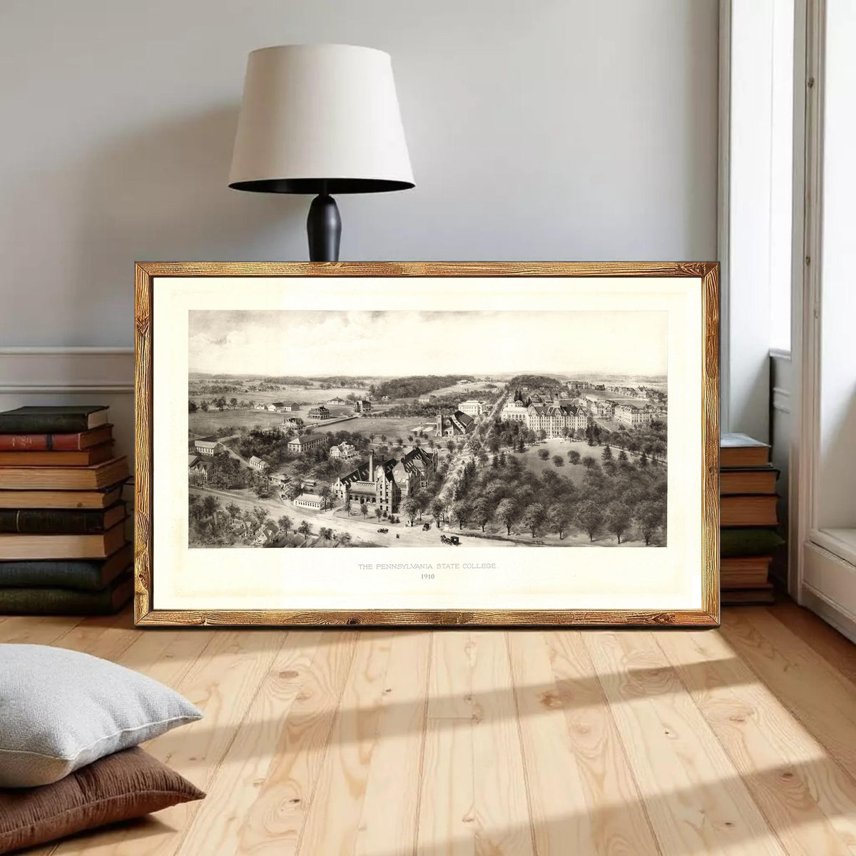 a large framed black and white illustration of a countryside landscape, with a lamp and bookshelf in the background.
