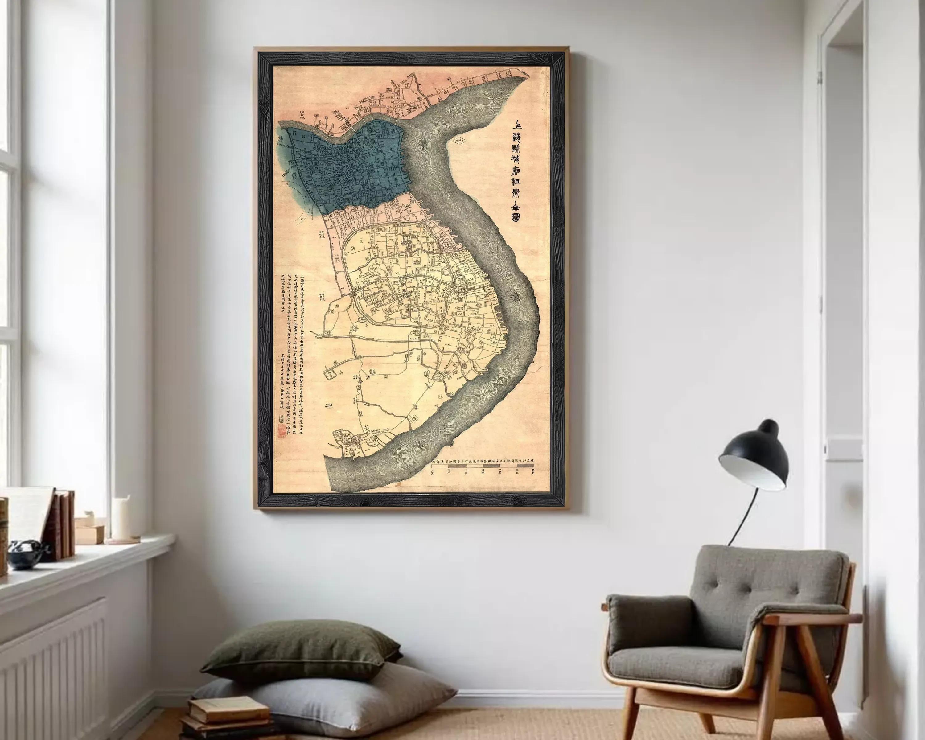The image is a framed map of a city, likely from an ancient Chinese or Japanese period, with a river running through it. The map appears to be in Chinese or Japanese script, and the frame has a black border. The map is displayed on a white wall, which contrasts with the colorful and detailed design of the map.