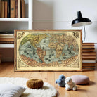 a large, old-fashioned world map displayed on a wooden stand, surrounded by various books and stuffed animals on a wooden floor.