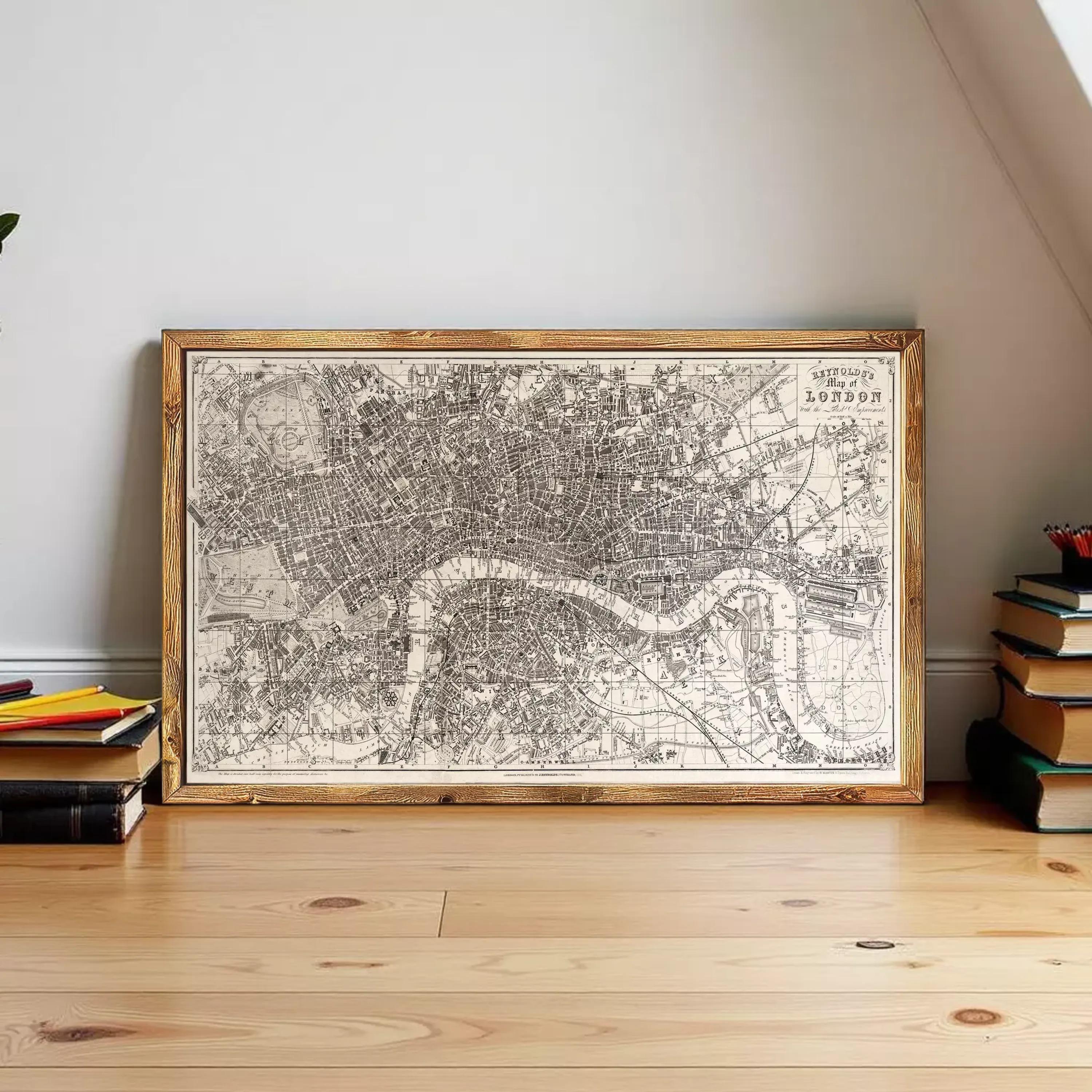 A large framed map of London is displayed on a wooden floor, surrounded by a stack of books.