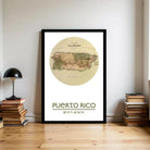A framed map of Puerto Rico is displayed on a wall, with a stack of books and a lamp to the left.