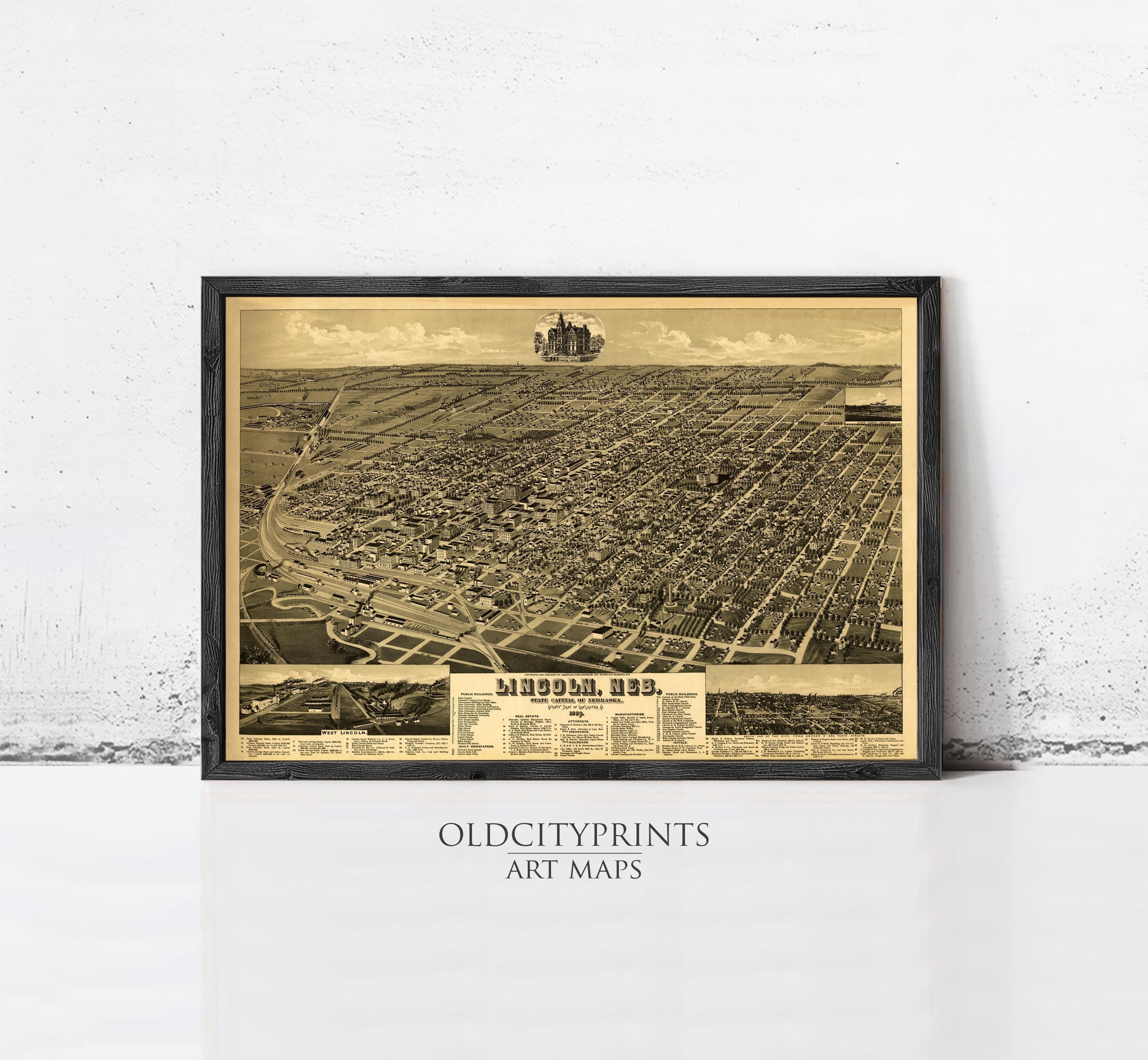 The image is a framed vintage map of a city, likely from the early 20th century, depicting a detailed aerial view of the urban landscape.