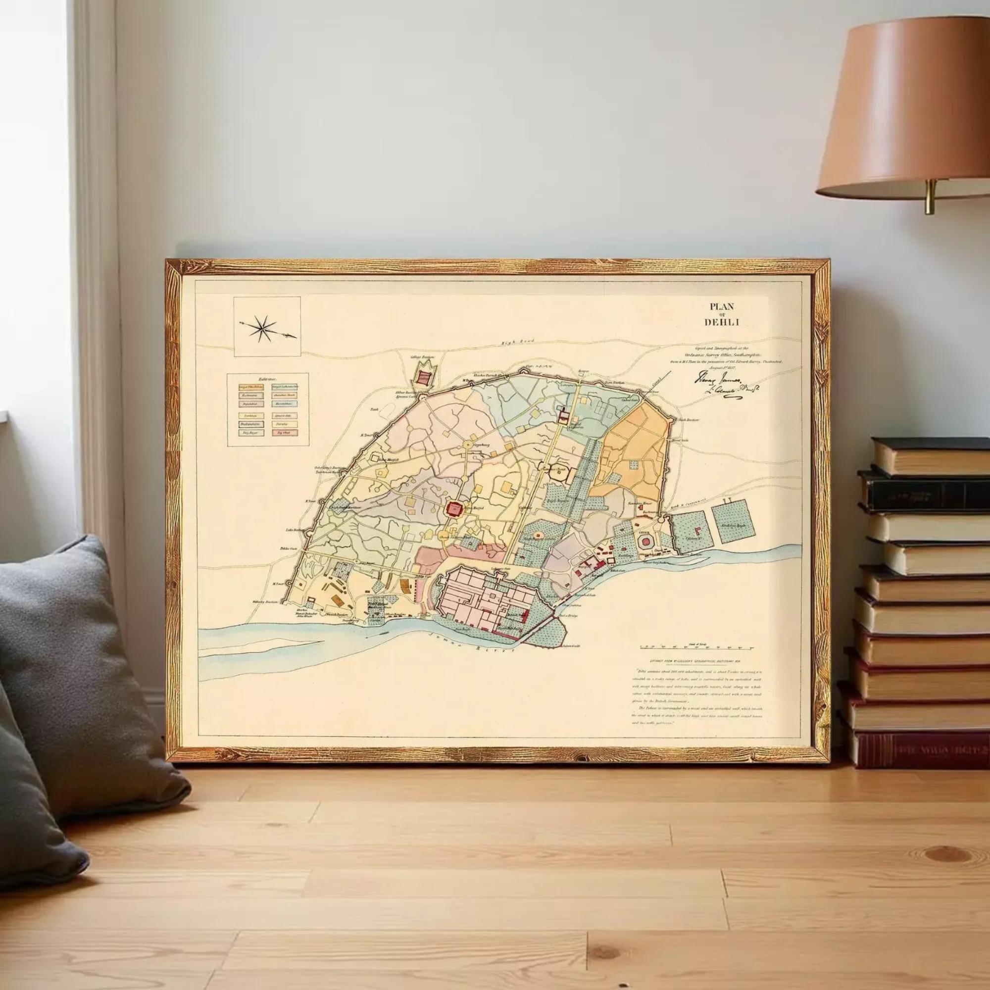 a framed map of a city or region, placed on a wooden floor next to a stack of books.