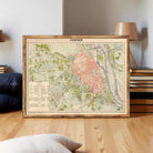 a framed map of Hanoi, Vietnam, displayed on a wooden floor in a room with a lamp and books in the background.