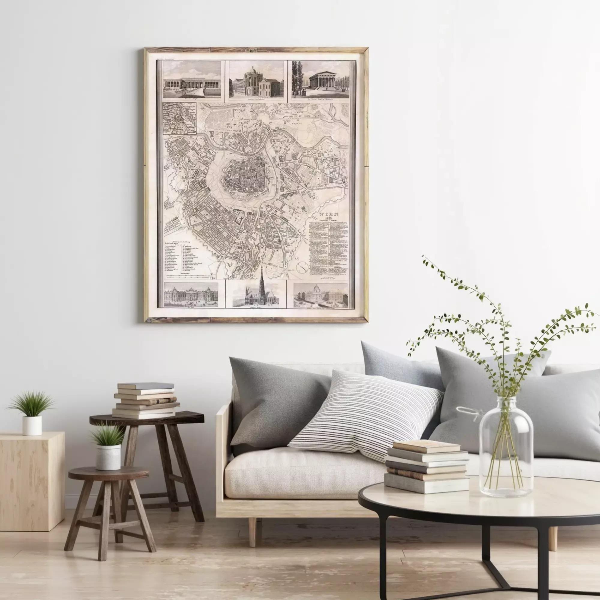 a living room with a large framed map hanging on the wall above a couch with pillows. There are also some books and a vase with greenery on the coffee table.