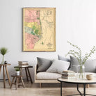 a living room with a framed map of the city of Montreal hanging on the wall. The room has a gray sofa, a coffee table, and a few decorative elements such as a vase with greenery and a stack of books.