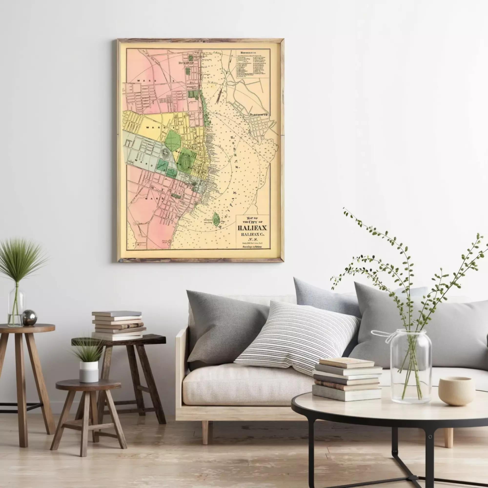 a living room with a framed map of the city of Montreal hanging on the wall. The room has a gray sofa, a coffee table, and a few decorative elements such as a vase with greenery and a stack of books.