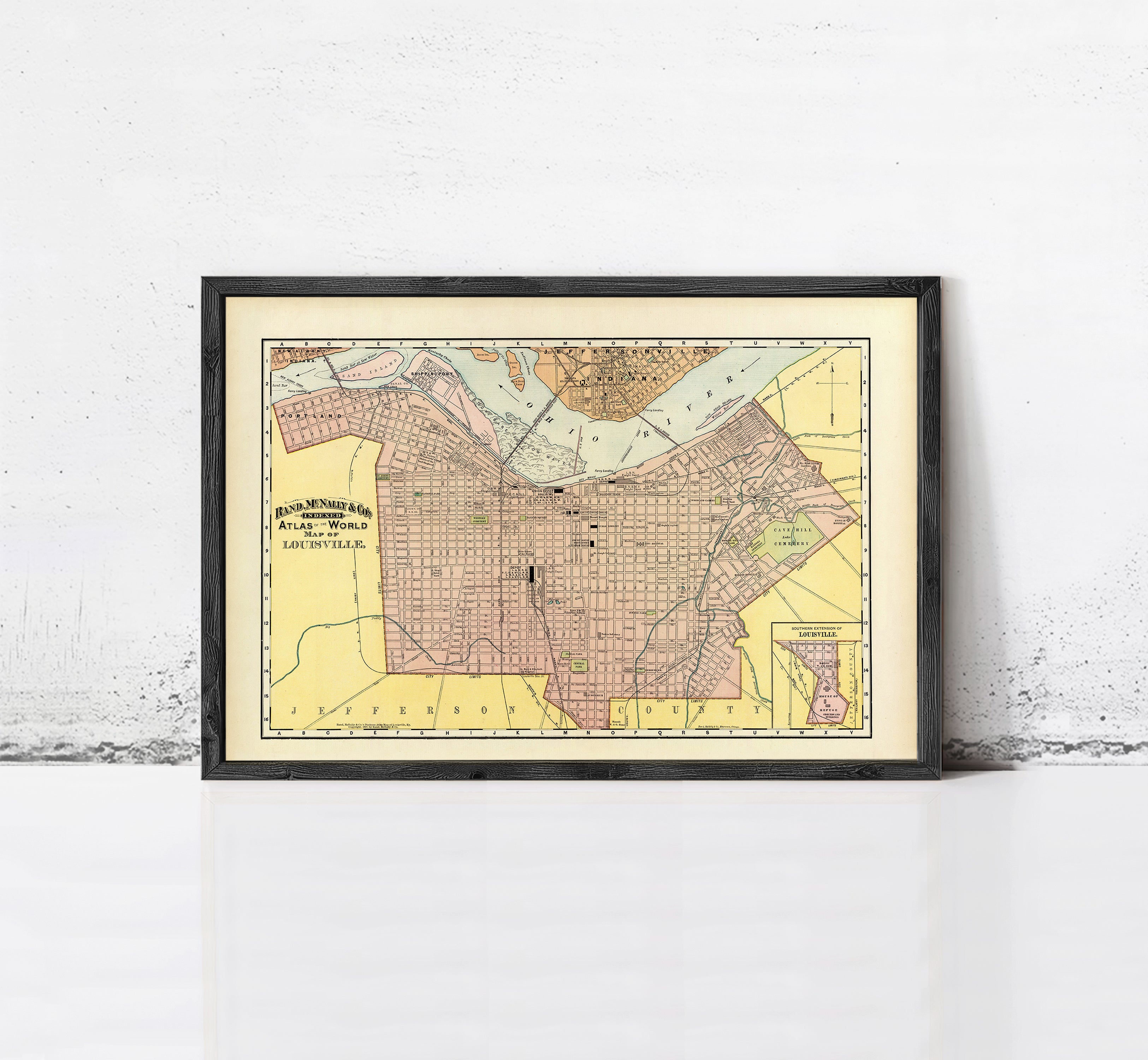 The image is a framed vintage map of a city, likely from the early 20th century, with a yellow and pink color scheme.