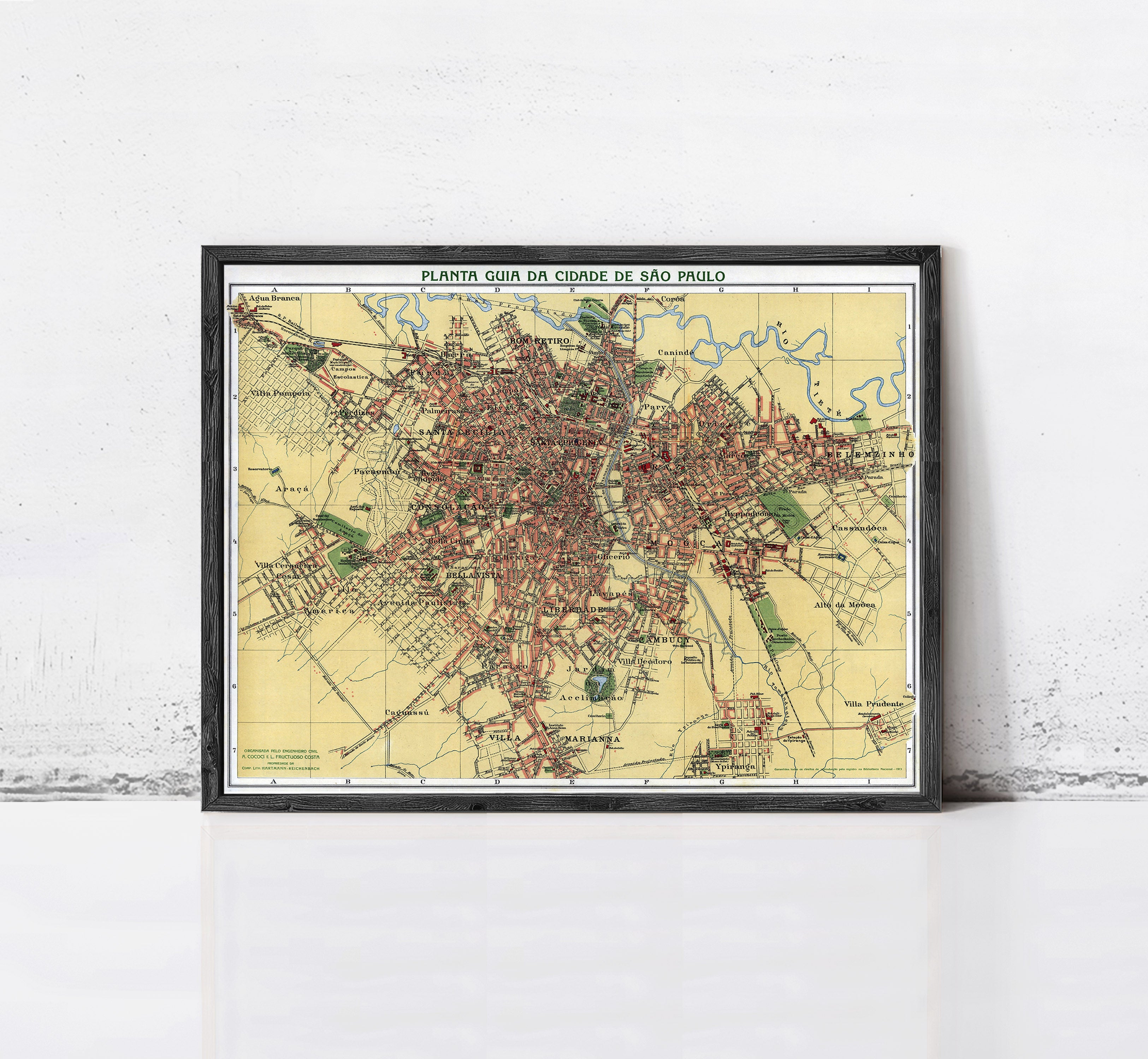 The image is a framed map of a city, likely from the early 20th century, depicting a detailed layout of the city's streets, landmarks, and other features.
