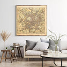a living room with a large framed map of Milan hanging on the wall above a couch with pillows. There are also some books and decorative items on the couch and table below the map.