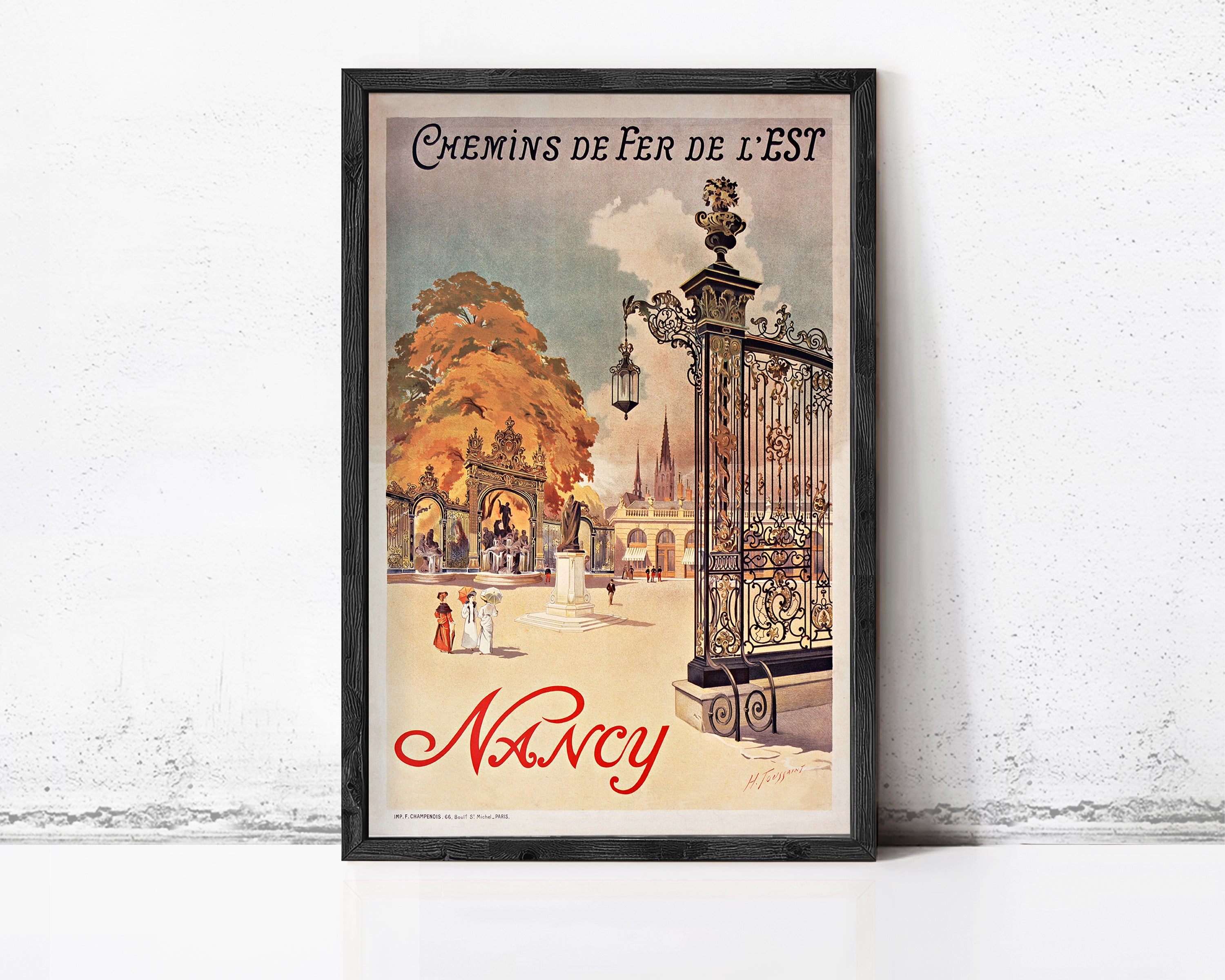 A framed vintage poster advertising Nancy, featuring an illustration of a park scene with people and a gazebo.