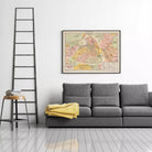 a gray sofa with a yellow blanket draped over it, and a framed map of Paris hanging on the wall above the sofa.