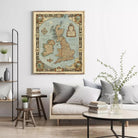 a living room with a large framed map of the United Kingdom hanging on the wall above a couch. The room has a minimalist and modern design, with a wooden coffee table, a bookshelf, and a vase with greenery.