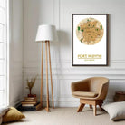 A cozy living room with a wooden floor lamp, a beige armchair, and a framed map of Fort Wayne, a city in the United States.