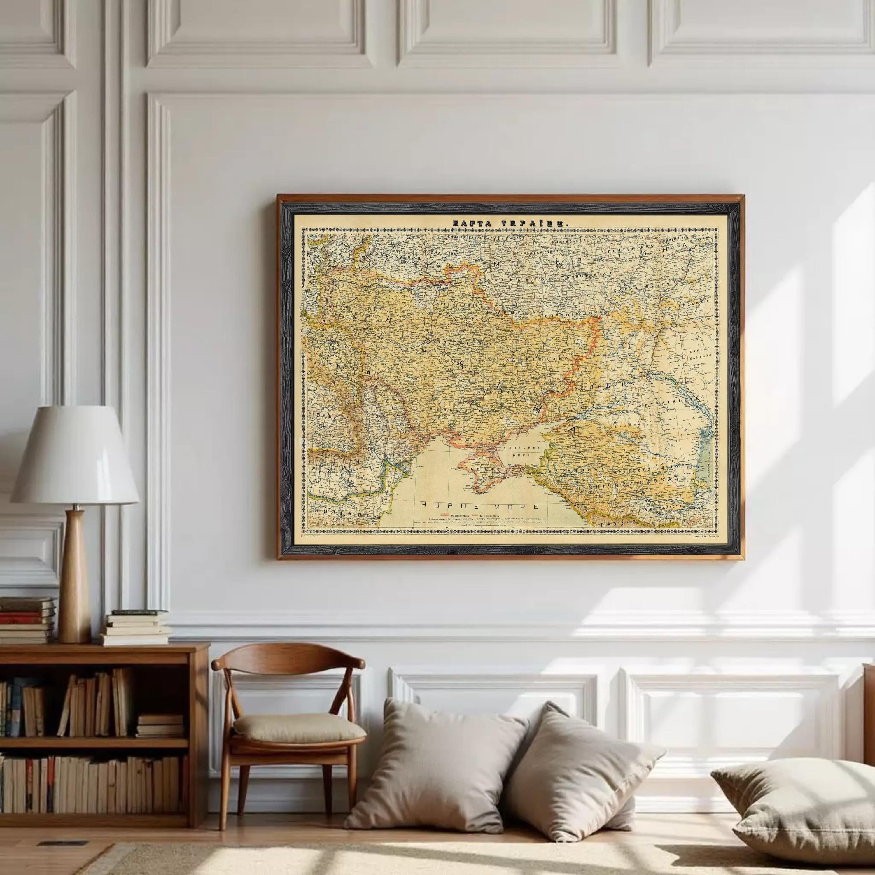 a large framed map of the world hanging on a white wall in a room with a wooden bookshelf, a wooden chair, and a lamp.