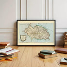A framed map of the Mediterranean region is displayed on a wooden floor, surrounded by various books and stationery items.