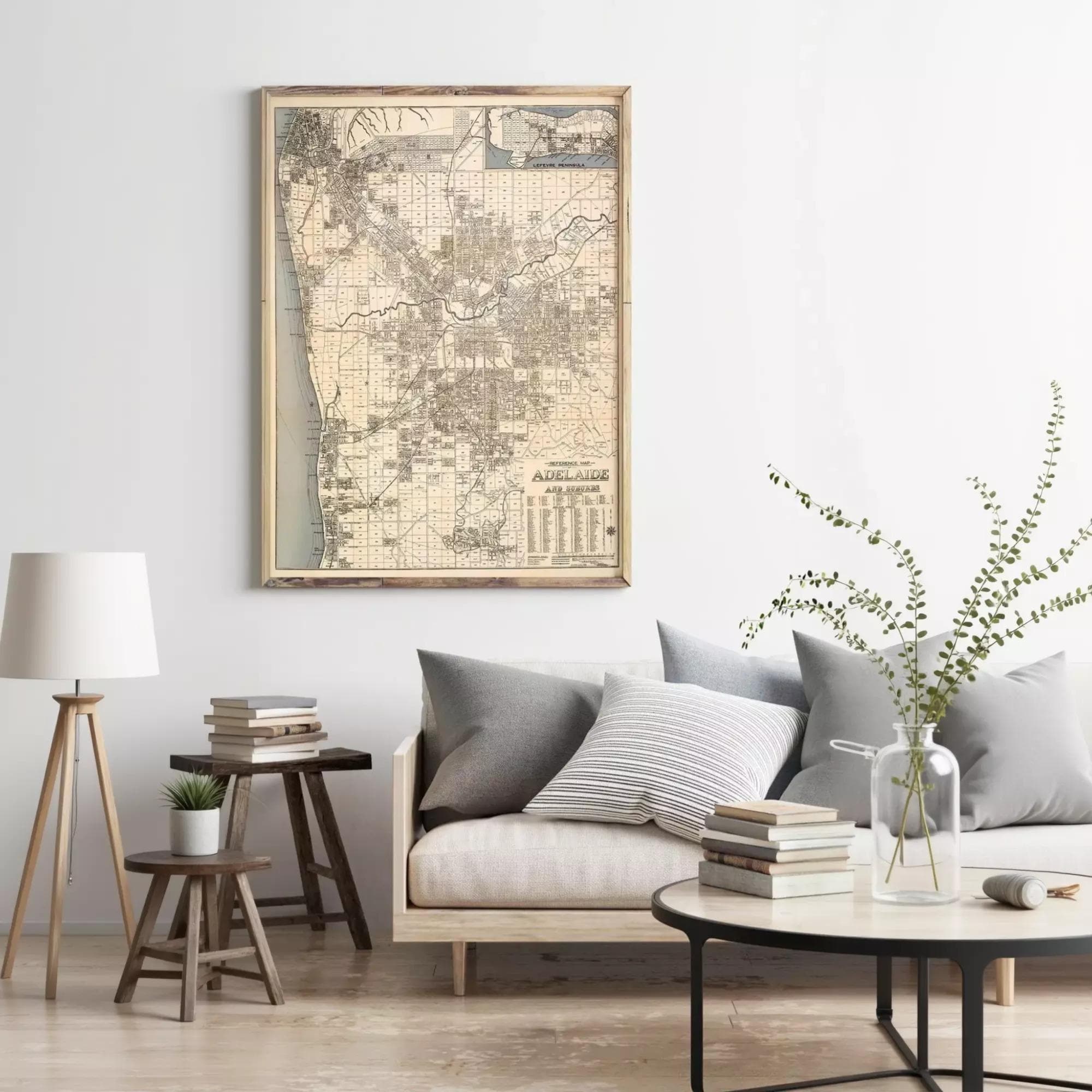 a living room with a large framed map of San Diego hanging on the wall above a gray sofa with striped pillows. The room also includes a wooden side table, a round coffee table, and a lamp.