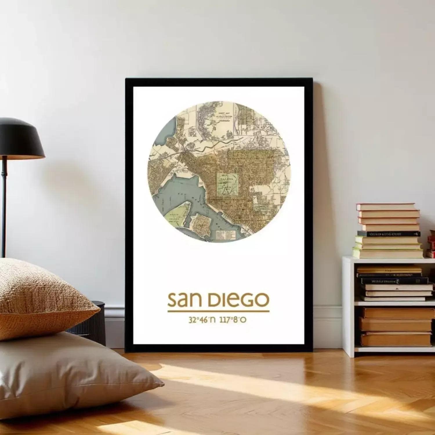 A framed map of San Diego, with the city's name and location prominently displayed, is hanging on a wall in a room with a lamp and bookshelf.